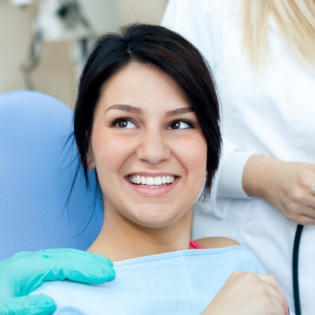 Woman smiling while she undergoes an oral cancer screening at Woburn Dental Healthcare