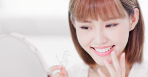 Photo of a woman holding an Invisalign aligner