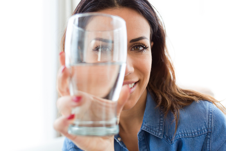 Dark-haired woman holding up a glass of water